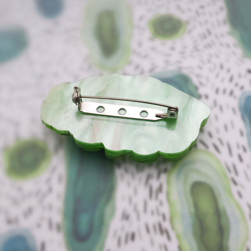 Back of green acrylic tardigrade brooch showing stainless steel broch pin