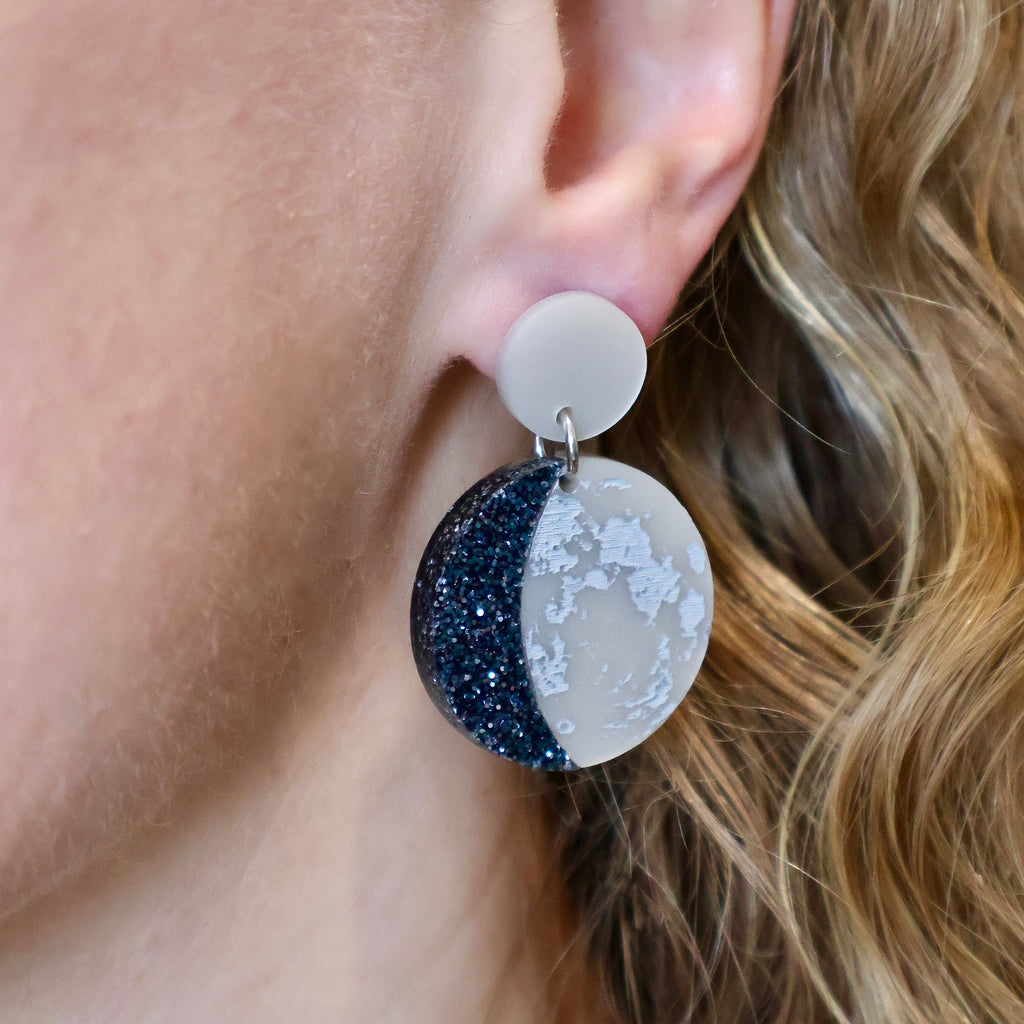 Acrylic moon phase earrings being modelled.