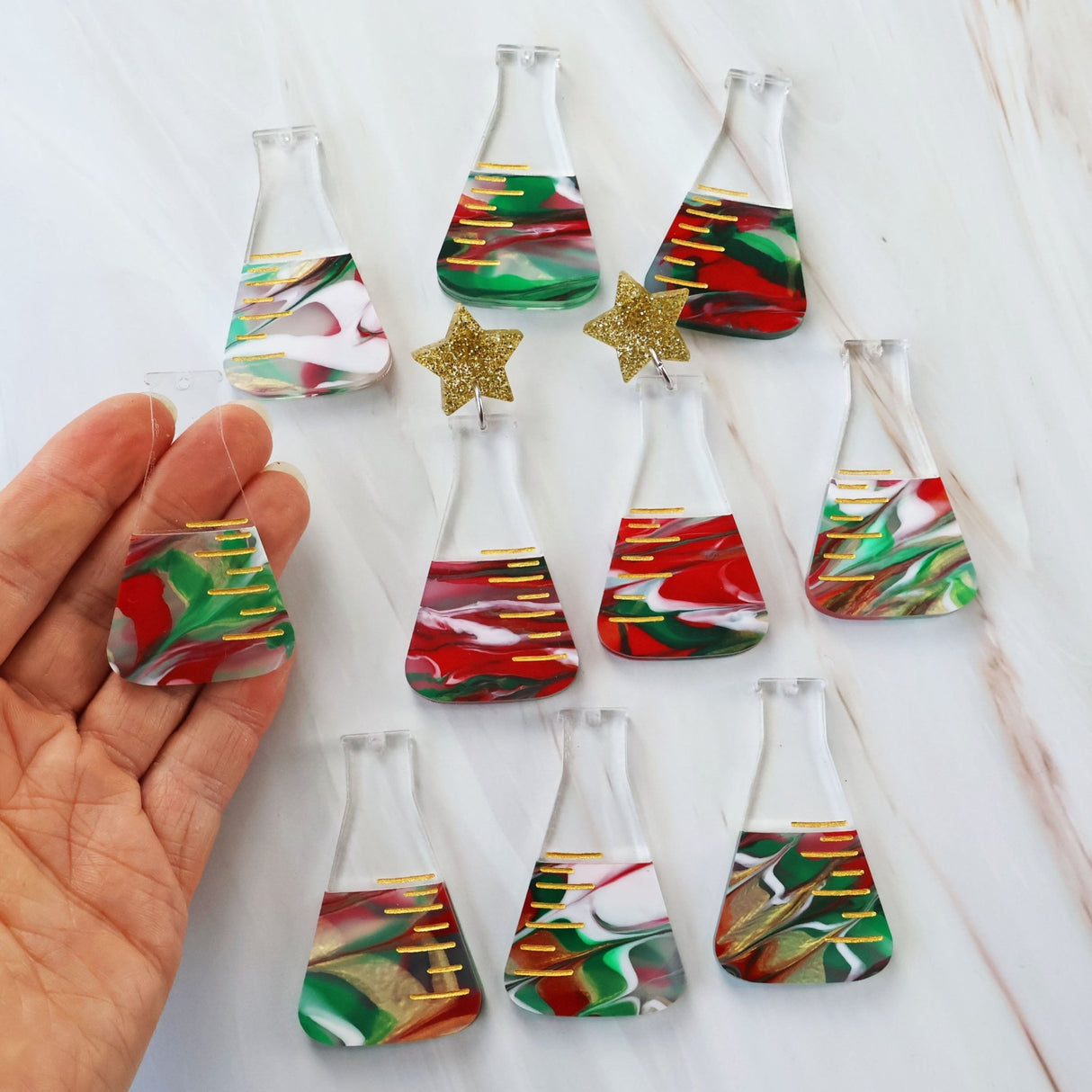 Photo showing the variation in colours across different pairs of dangle earrings featuring a conical flask design with Christmas-themed decorations.
