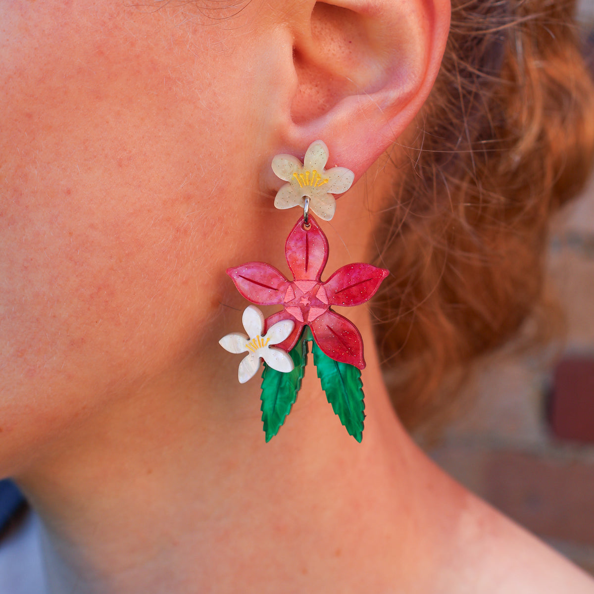A woman modelling a pair of acrylic Christmas bush earrings