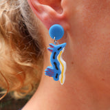 A pair of chromodoris sea slug acrylic earrings being modelled