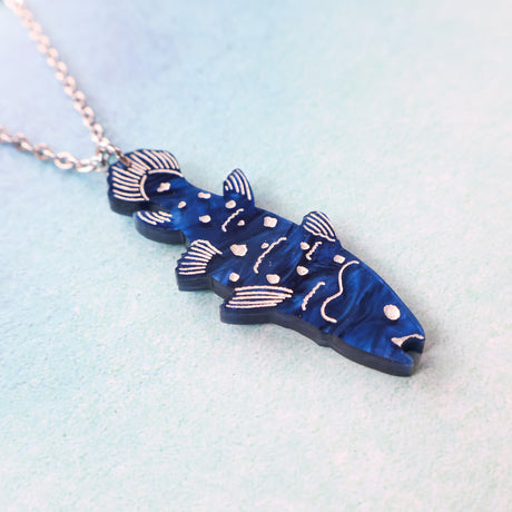 Blue fish-shaped pendant on a chain against a light blue background