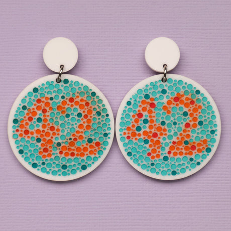Pair of earrings with colour blindness test design featuring dots in orange and blue showing the number 42 on a purple background