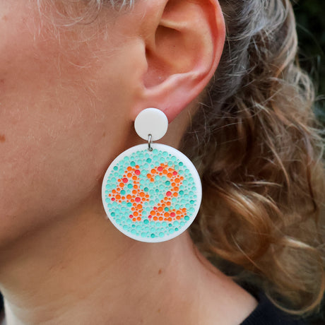 Close-up of a person wearing a colourful colourblindness test earring with the number 42.