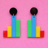Colourful column graph-shaped earrings with round black toppers on a pink background