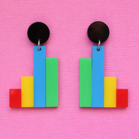 Colourful column graph-shaped earrings with round black toppers on a pink background