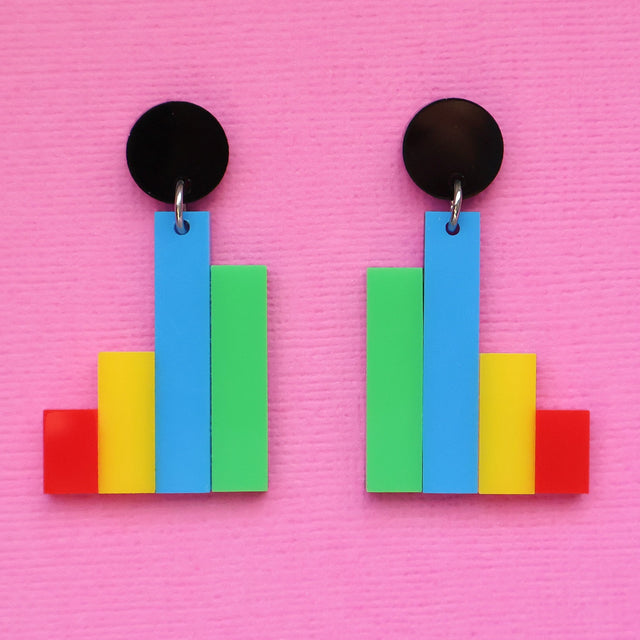 Colourful column graph-shaped earrings with round black toppers on a pink background