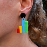 Colorful column graph acrylic earrings worn by a person.