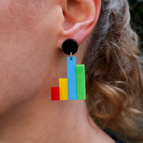 Colorful column graph acrylic earrings worn by a person.
