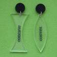 A pair of acrylic earrings labeled 'concave' and 'convex' on a green background, with black acrylic toppers. 