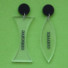 A pair of acrylic earrings labeled 'concave' and 'convex' on a green background, with black acrylic toppers. 