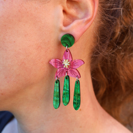 A woman modelling a pair of crowea flower earrings in acrylic. 