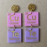 Pair of earrings with periodic table elements spelling CuTe in purple, pink and gold tones. 