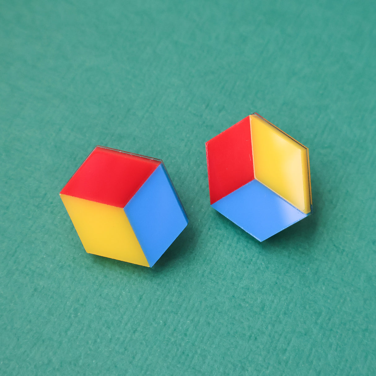 Colorful cube red yellow and blue geometric earrings on a green background