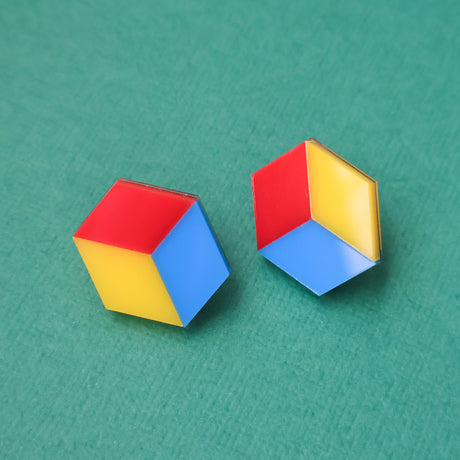 Colorful cube red yellow and blue geometric earrings on a green background
