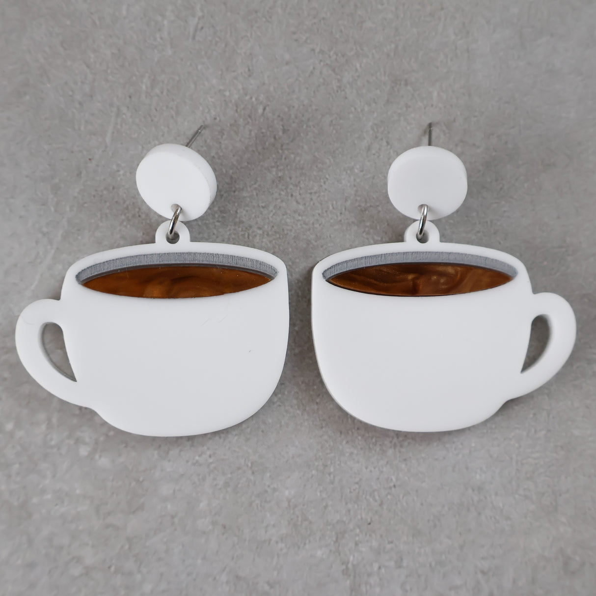 White coffee cup earrings with brown center and white round toppers on a grey background