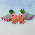 Colourful cuttlefish shaped earrings on a light blue background
