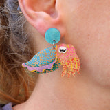 A laser cut acrylic cuttlefish earring being modelled. 