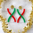 Acrylic DNA strand earrings  in red green and gold tones, on a textured white surface with gold tinsel around them