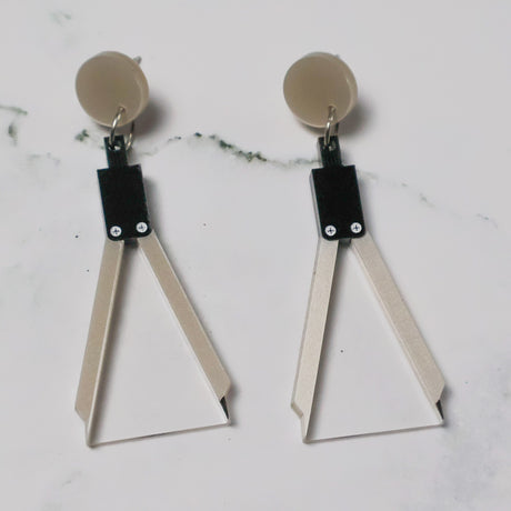 A pair of acrylic earrings shaped like a set of drawing compasses.