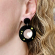 Oh Pluto logo earrings being modelled.