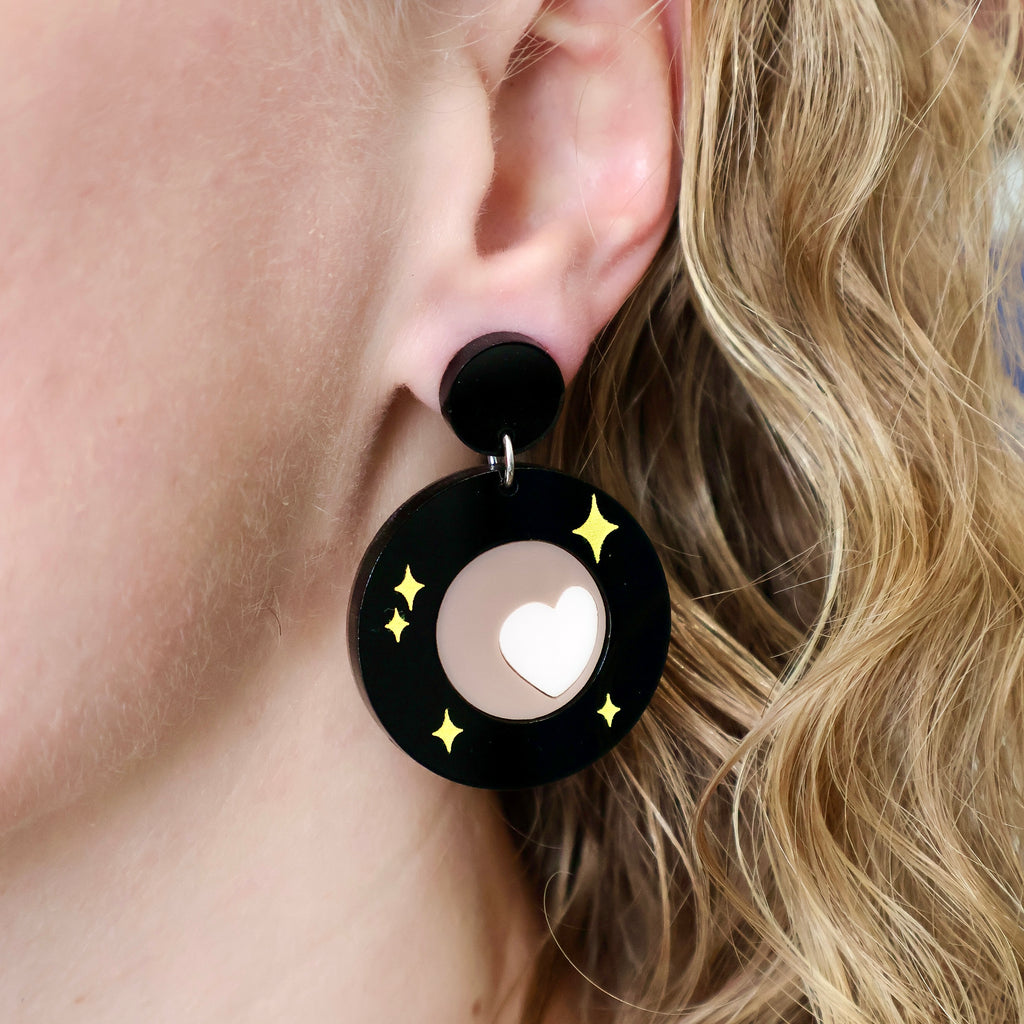 Oh Pluto logo earrings being modelled.