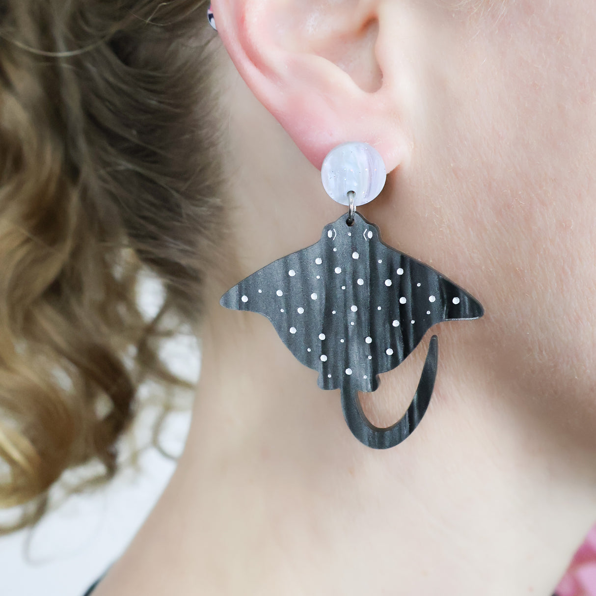 Laser cut arylic eagle spotted ray dangle earrings being modelled.