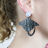 Laser cut arylic eagle spotted ray dangle earrings being modelled.