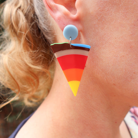 A wedge shaped earring representing a cross sectional view through layers of the earth to its core, being modelled. 