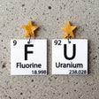 black and white asymmetrical periodic table earrings with 'Fluorine' and 'Uranium' labels, and yellow star toppers. 