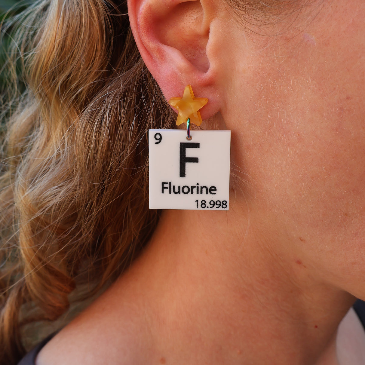 Person wearing a 'Fluorine' earring with a star-shaped element