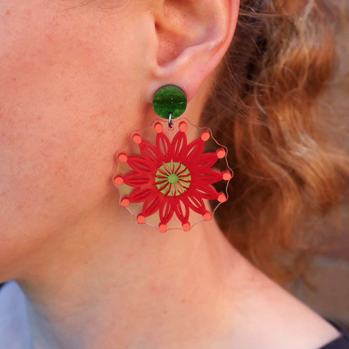 A woman modelling a pair of Firewheel Tree flower earrings