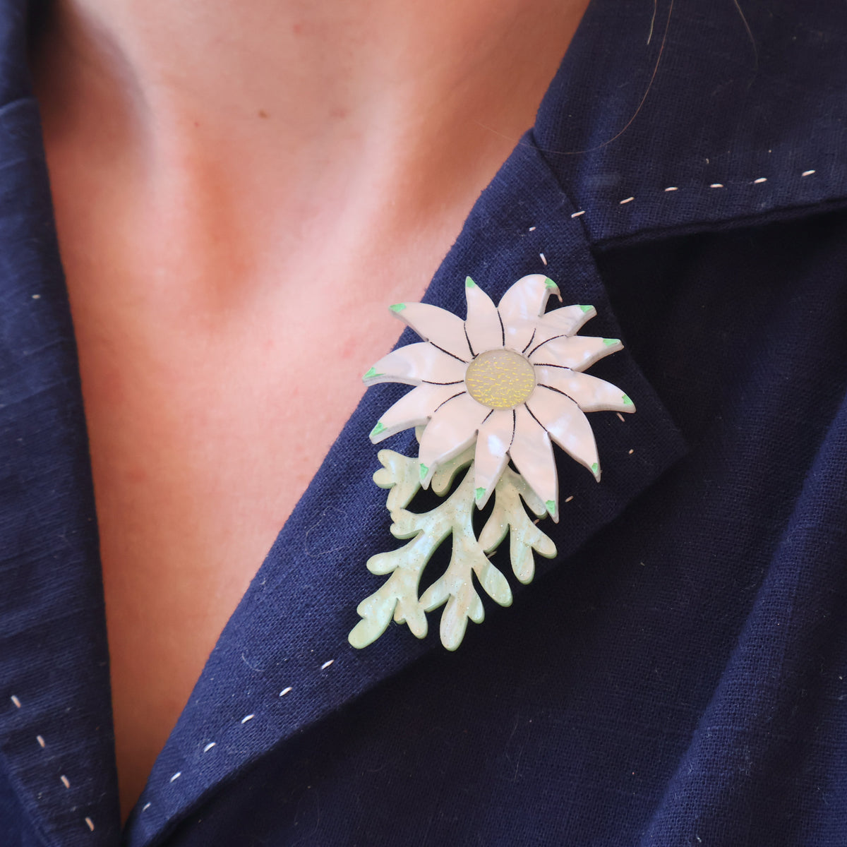 Acrylic flannel flower brooch being worn on a blue collar.