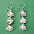 Close-up photo of a pair of garlic earrings. 3 garlic bulbs dangle from each French hook. 