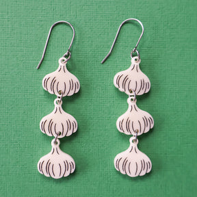 Close-up photo of a pair of garlic earrings. 3 garlic bulbs dangle from each French hook. 