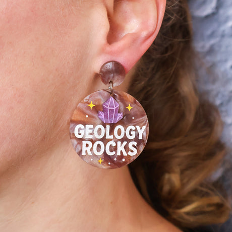 Earring with 'GEOLOGY ROCKS' text worn by a person