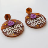 Earrings with 'Geology Rocks' text and gemstone designs on a white background
