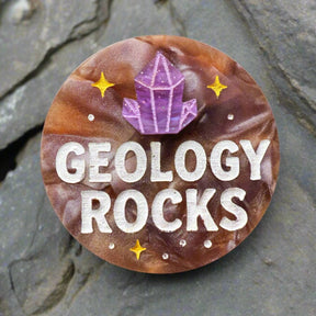 Acrylic brooch with 'Geology Rocks' text and a purple crystal design