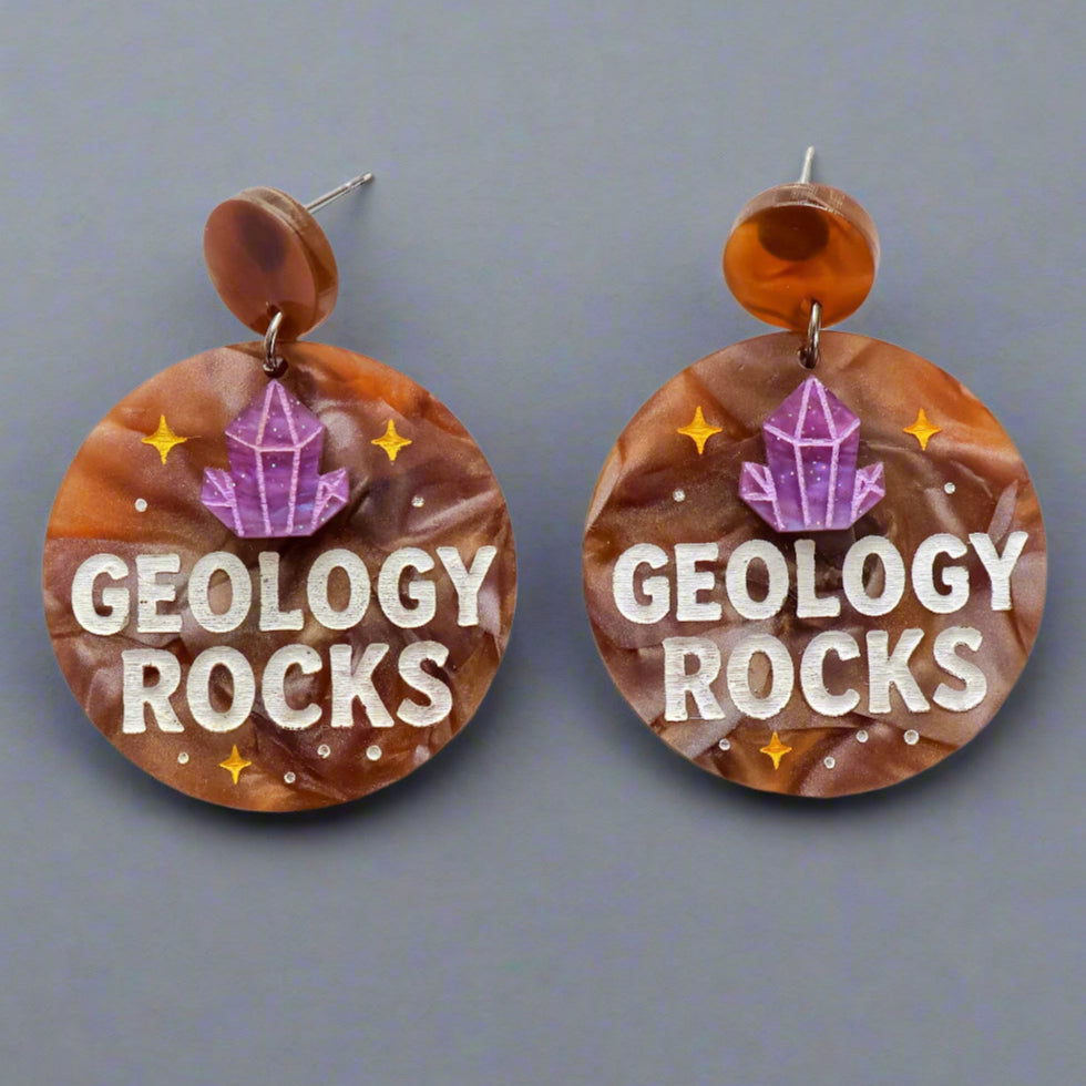 Earrings with 'Geology Rocks' text and a crystal design on a gray background
