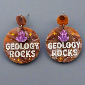 Earrings with 'Geology Rocks' text and a crystal design on a gray background