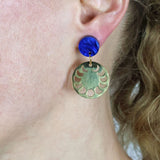 A pair of earrings with blue acrylic round toppers and round gold toned stainless steel moon phase dangles.