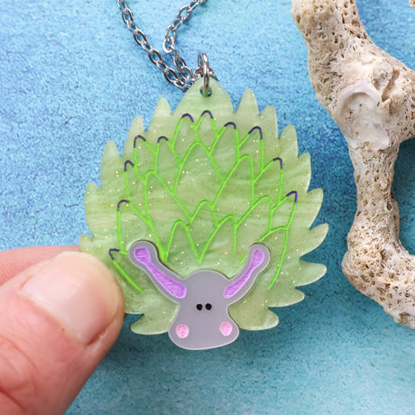 Leaf sheep-shaped pendant with green spikes and purple accents on a blue background