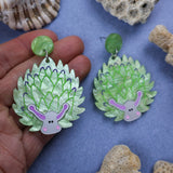 Laser cut acrylic leaf sheep earrings, being held up in hand.