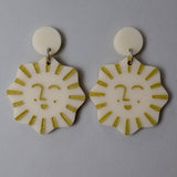 Pair of tan and gold acrylic earrings with smiling sun design 