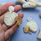 Laser cut acrylic hermit crab earrings, being held up. 