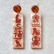 Pair of earrings with Egyptian hieroglyphics on a marble background