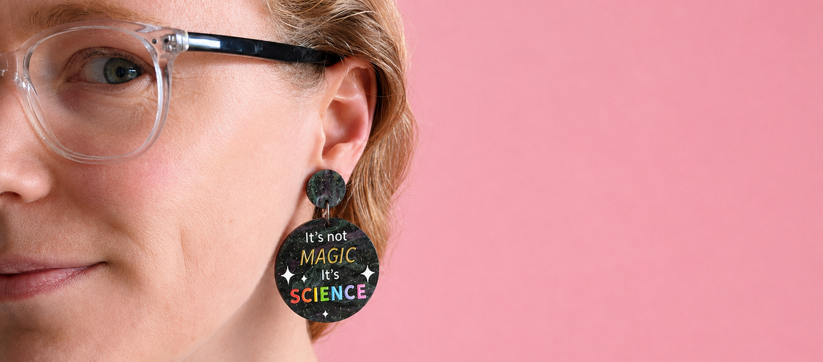 Its not magic its science earrings being modelled against a pink background for front website banner