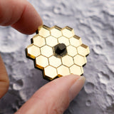 JWST mini acrylic laser cut brooch brooch being held for scale, showing gold mirror acrylic, against a moonscape background.