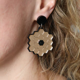 James Webb Space Telescope Earrings constructed from gold mirror acrylic and black acrylics, being modelled. 