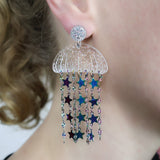 Glittery Acrylic jellyfish earrings with rainbow star chain, being modelled. 